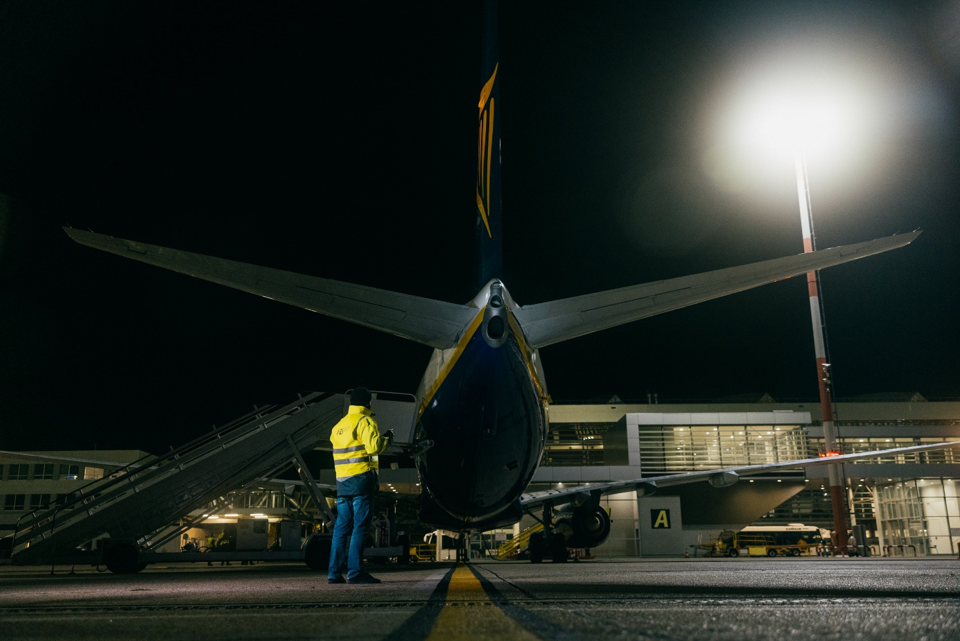 Technician standing behind an aircraft on the apron at night