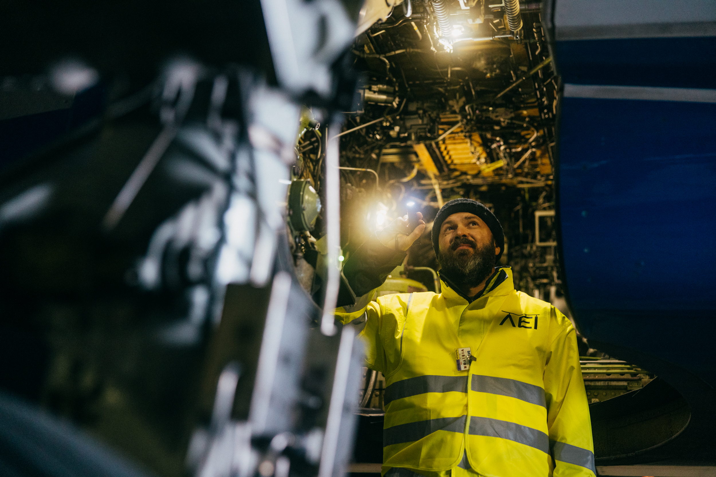 AEI technician inspecting an aircraft structure with a flashlight