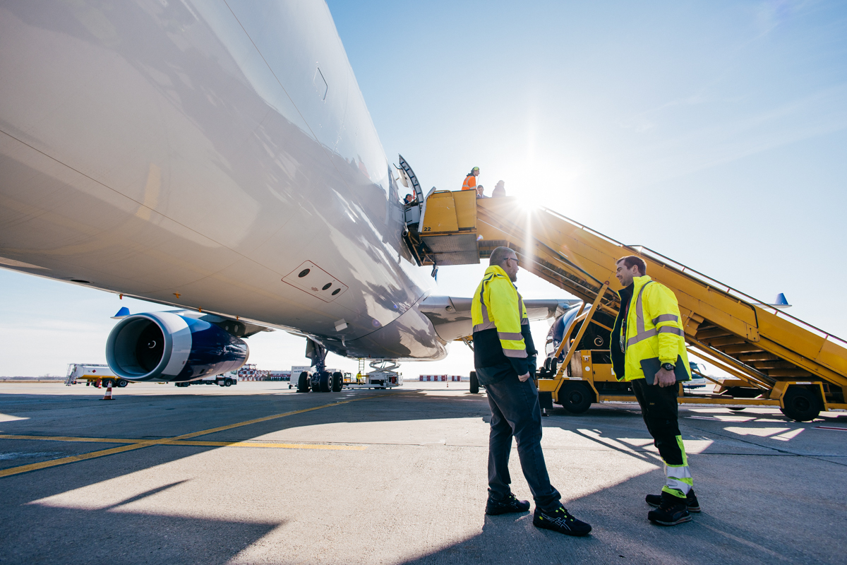 Two technicians talking beside an aircraft and boarding stairs